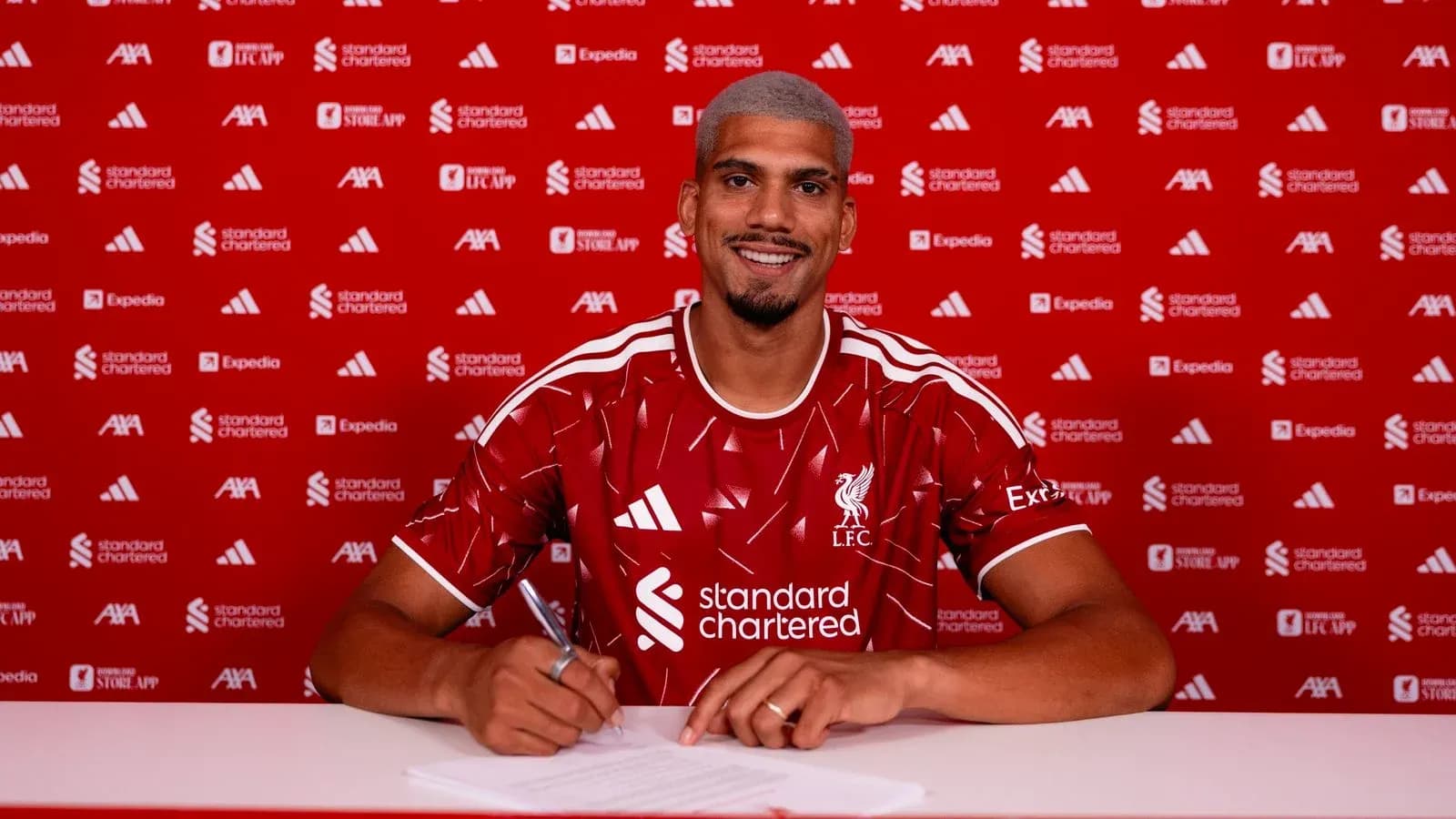 Jugador firmando contrato con camiseta de Liverpool Jugador firmando contrato con camiseta de Liverpool